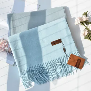 Close-up of soft cashmere-like scarves with fringe details in light blue and grey tones