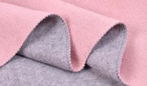 Dettaglio macro della sciarpa in cashmere bicolore rosa e grigio con cuciture overlock