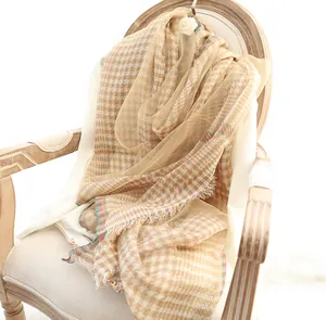 Macro shot of light brown checkered silk scarf with fringe and subtle stripes on a chair