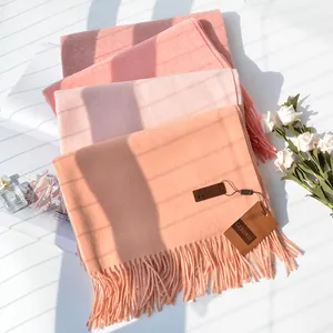 Detail of pink cashmere-feel scarf texture with soft fringes and brand label