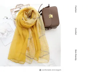 Flat lay of yellow silk wool blend scarf with stripe pattern and vintage accessories