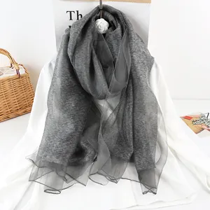 Dark grey silk mohair shawl scarf draped over a white shirt in a minimalist home setting