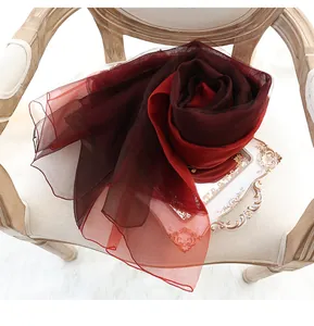 Détail d'une écharpe en soie dégradé rouge en forme de rose sur une chaise vintage