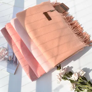 Detail of soft cashmere feel scarves in coral and pink tones with elegant fringe edges