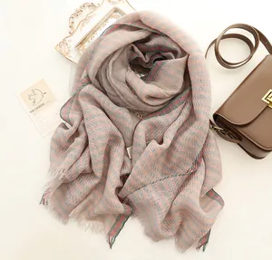 Long silk scarf with plaid stripes and fringe detail paired with a leather bag