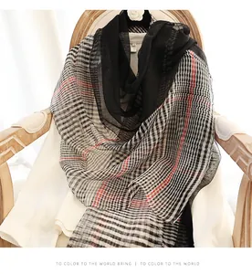 Close-up of translucent silk wool plaid scarf with red stripes on wooden chair