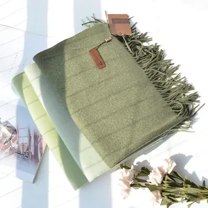 Detailed macro view of soft cashmere scarf layering in shades of green with fringe edge