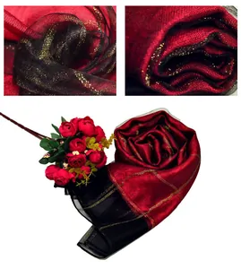 Detail view of red and black silk scarf featuring gold glitter stripes and sheer texture