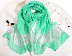 Detail of green silk scarf with golden stripes and 100% silk label on plush background