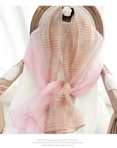 Detail of a sheer silk wool scarf with pink and beige stripes draped on a vintage chair