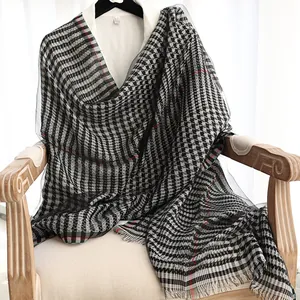 Houndstooth silk scarf with red accents and tassel edges draped over a white shirt