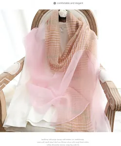 Detail of silk wool blend plaid scarf in pink and khaki draped over a white shirt
