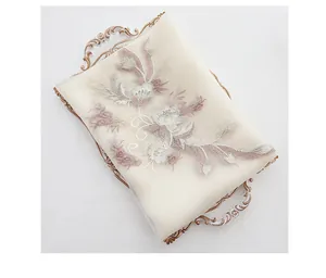Detailed close-up of intricate 3D floral embroidery on a cream silk wool luxury shawl
