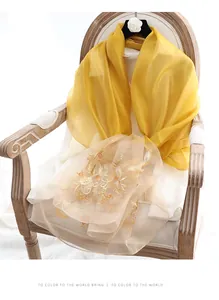 Close-up of elegant bright yellow silk wool scarf featuring fine floral embroidery detail