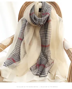 Detail of checkered silk wool scarf with red stripes over a white shirt on a chair