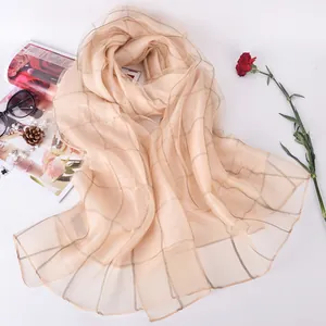 Elegant champagne silk scarf with gold grid pattern, pearls and sunglasses flat lay