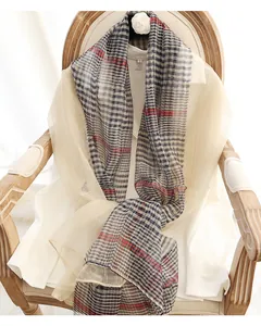 Detail of silk wool plaid scarf draped on a vintage chair with soft indoor lighting