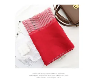 Macro shot of silk and wool red scarf featuring checkered borders and elegant textures