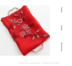 Detail view of red silk wool scarf with floral embroidery on a golden vintage tray