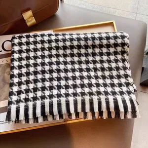 Détail de l'écharpe pied-de-poule noir et blanc avec franges dans un plateau élégant