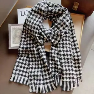 Détail du motif pied-de-poule doux et des franges délicates sur l'écharpe d'hiver