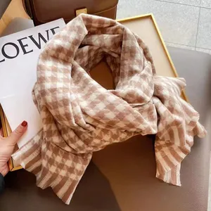 Texture détaillée de l'écharpe en pied-de-poule marron avec pompons dans un décor de luxe