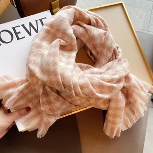 Détail de l'écharpe pied-de-poule rose et blanc avec franges sur un plateau décoratif