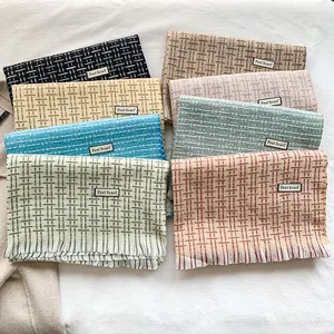 Dettaglio di sciarpe colorate con frange, etichetta Feel Scarf e trama morbida