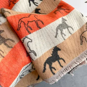 Macro detail of horse pattern scarf showing thick cashmere texture and fringe tassels
