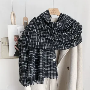 Elegante sciarpa a quadri neri e bianchi con frange su appendino in legno e cappotto