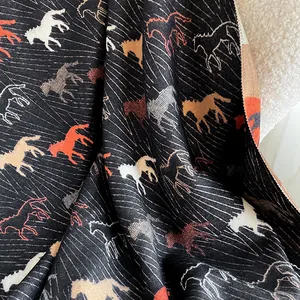 Detailed view of black cashmere feel scarf featuring vibrant running horse printed patterns