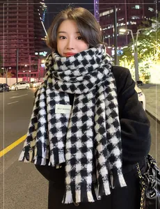 Close-up of houndstooth scarf with fringe detail and a white rectangular fabric label