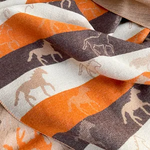 Close-up of soft cashmere-like scarf with elegant orange horse jacquard patterns