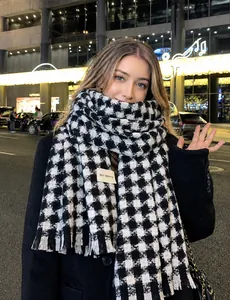 Close-up of black and white houndstooth scarf with fringe and Self Service label