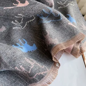 Detail of dark grey faux cashmere scarf featuring pink deer jacquard and fringe edges