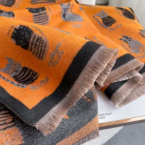 Close-up of thick orange cat jacquard knit scarf with long fringe and soft texture