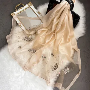 Détail d'une élégante écharpe en soie champagne avec broderie florale et texture brillante