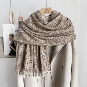Dettaglio di sciarpa a quadri beige con frange su un elegante cappotto di lana invernale