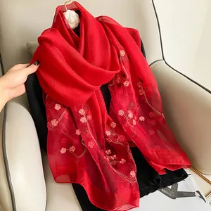 Détail d'un châle en soie rouge avec broderie florale délicate et fils dorés élégants