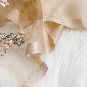 Détail de la broderie florale sur une écharpe en soie champagne légère avec maille fine