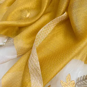 Detail of silk wool scarf showing golden diamond texture and embroidered leaf patterns
