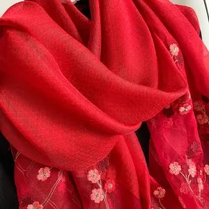 Vue détaillée d'une écharpe en soie et laine rouge avec broderie florale rose
