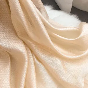 Détail d'une écharpe en soie champagne avec motif jacquard diamant et texture de luxe