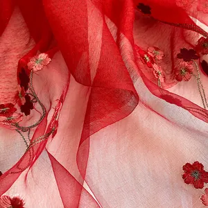 Détail macro d'une écharpe en soie et laine rouge avec broderie florale et texture fine