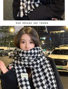 Detail of black and white houndstooth knit scarf with fringe and brand label