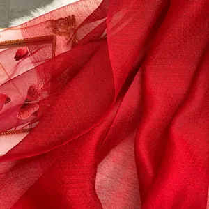 Detail of red silk wool scarf featuring delicate butterfly embroidery on translucent fabric