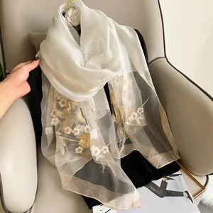 Close-up of silk wool shawl featuring 3D floral embroidery and elegant gold edging