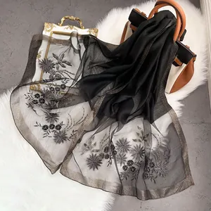 Detailed close-up of intricate flower embroidery on elegant black silk wool shawl