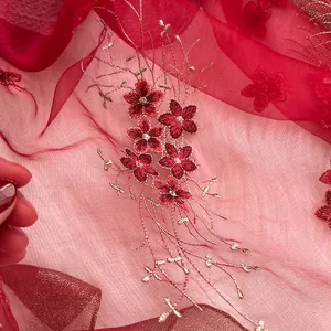 Gros plan détaillé d'une écharpe en soie rouge avec broderie florale or et rouge