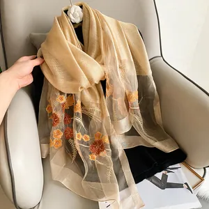 Detail of champagne silk wool shawl with orange floral embroidery and sequin embellishments